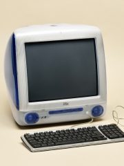 Apple iMac G3 computer from 1998 in original Indigo blue color. Retro computer with keyboard and mouse isolated on beige background